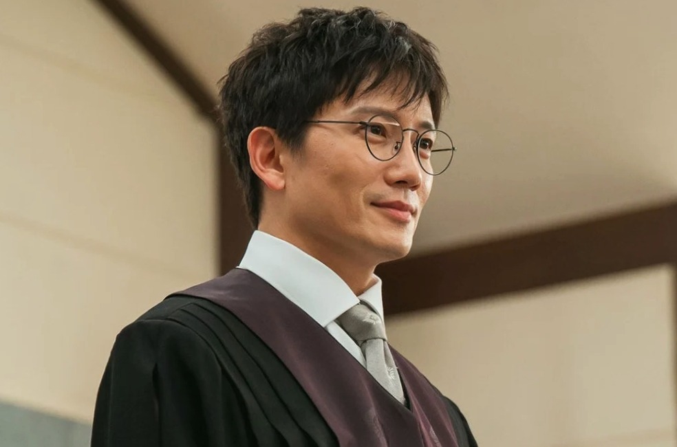 The main male lead of The Judge Returns is standing smiling