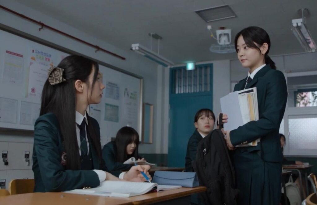The main leads are shown in Friendly Rivalry while one is sitting on the bench and one is standing and talking smilingly