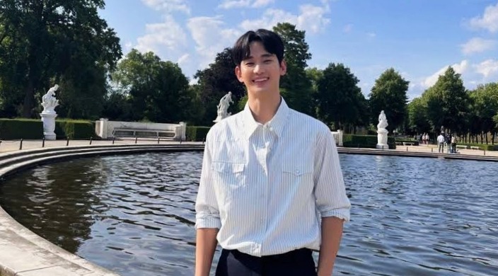 Kim Soo-hyun is standing straight and is smiling the background is fantasy palace